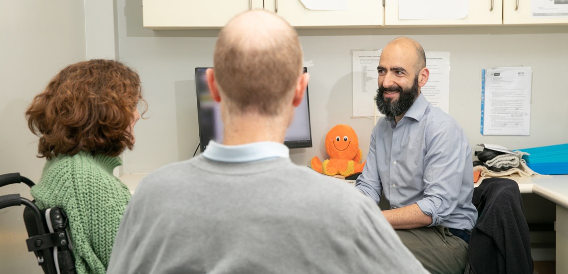 From left to right: trial participant Ailsa Guidi, sitting on a wheelchair. Next to her sits her partner Rob Guidi. On the right is trial physician Dr Sean Mangion, smiling. Image courtesy of the UK MS Society.